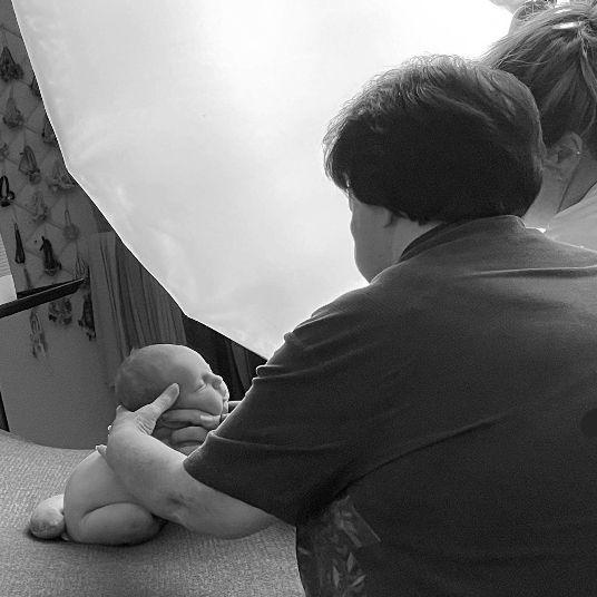 Black and white photo showing a caregiver performing infant care in a medical setting.