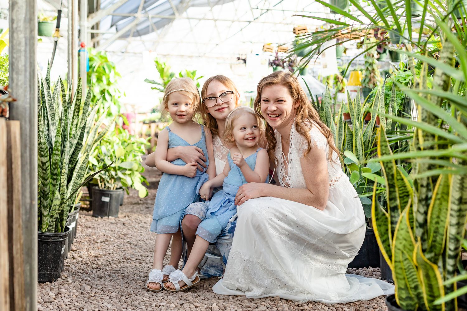 Mom snuggles with her teen and toddler daughters in a greenhouse in Colorado Springs, Colorado.
