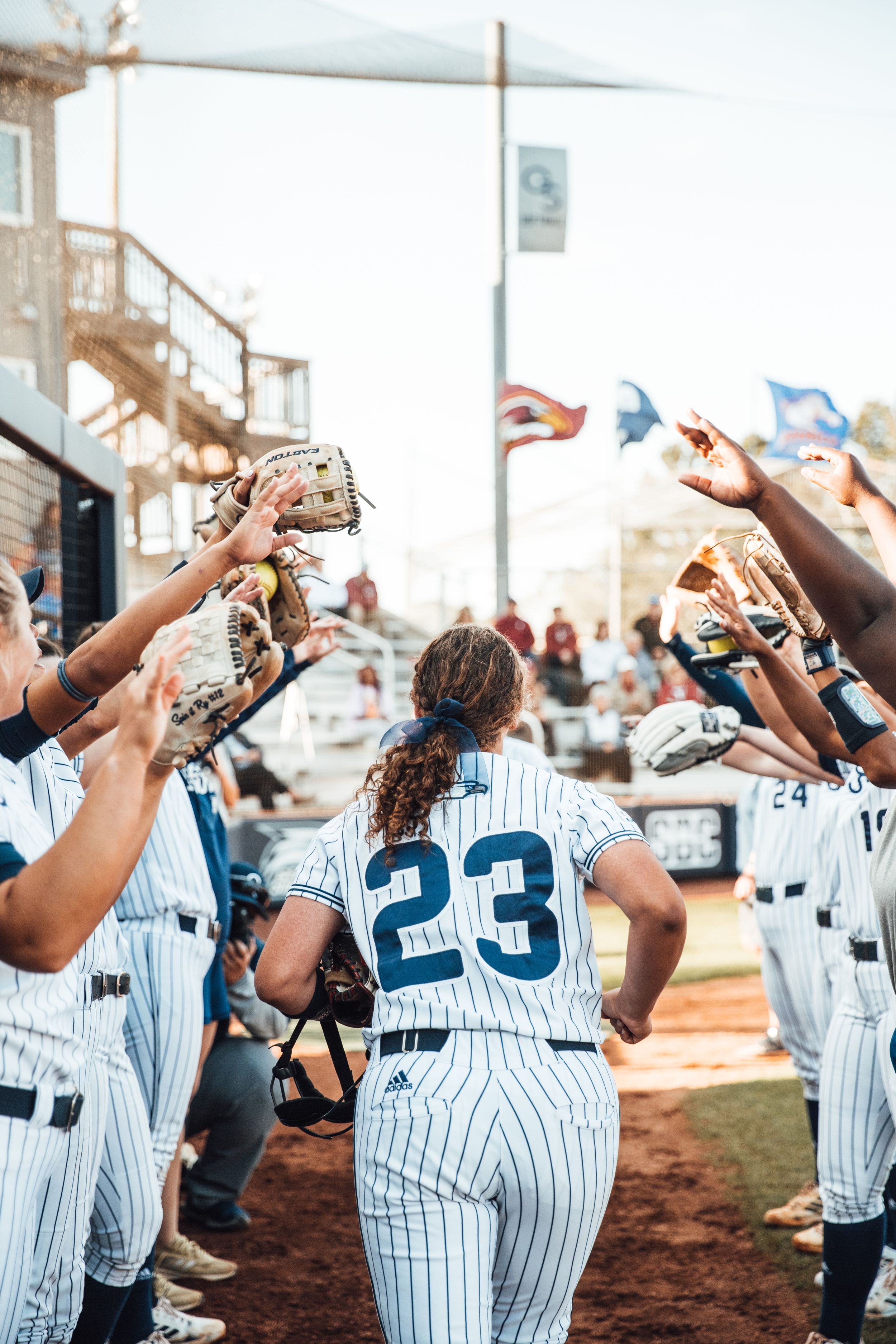 Softball team members in pinstripe uniforms celebrating before a game.