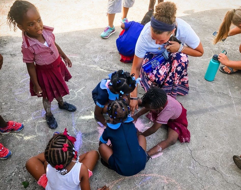 Kids and adults gathered together on pavement for an outdoor activity.