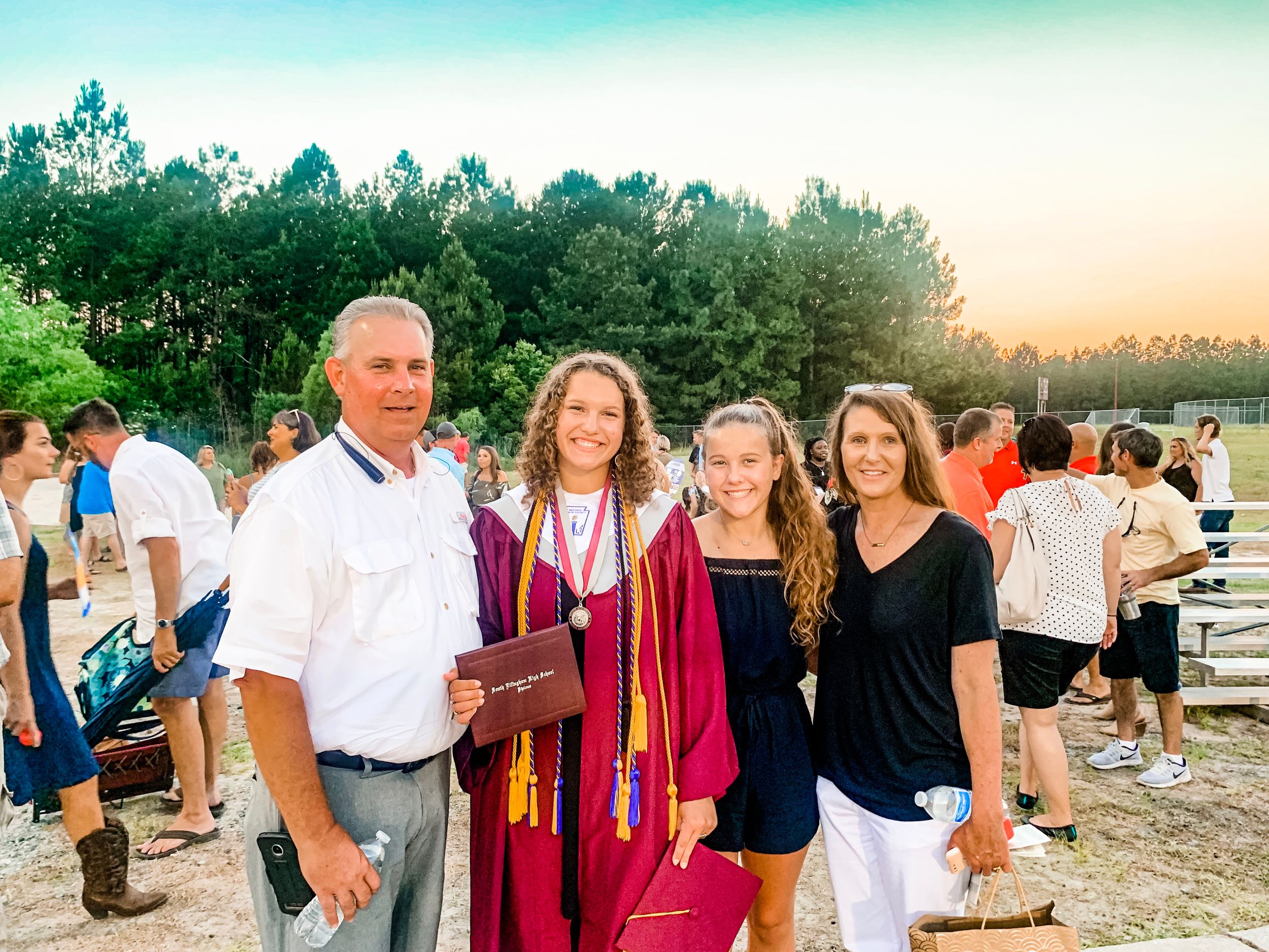A graduation celebration gathering outdoors at sunset with family.