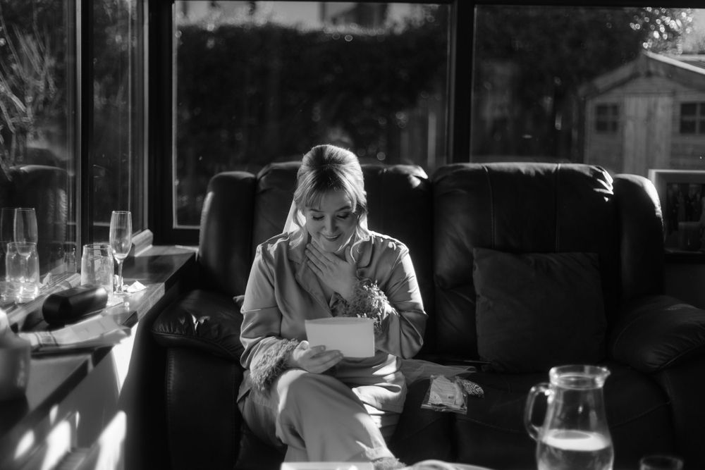 Black and white photo of peaceful morning reading by a window.