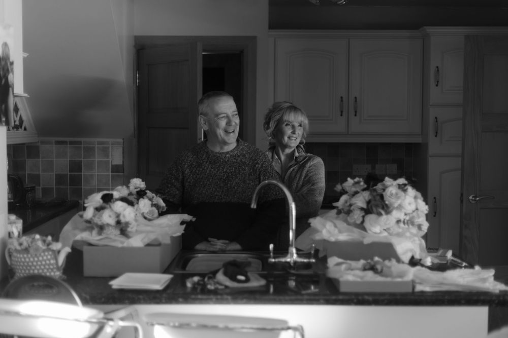 Vintage black and white photo of two people preparing food in a kitchen.
