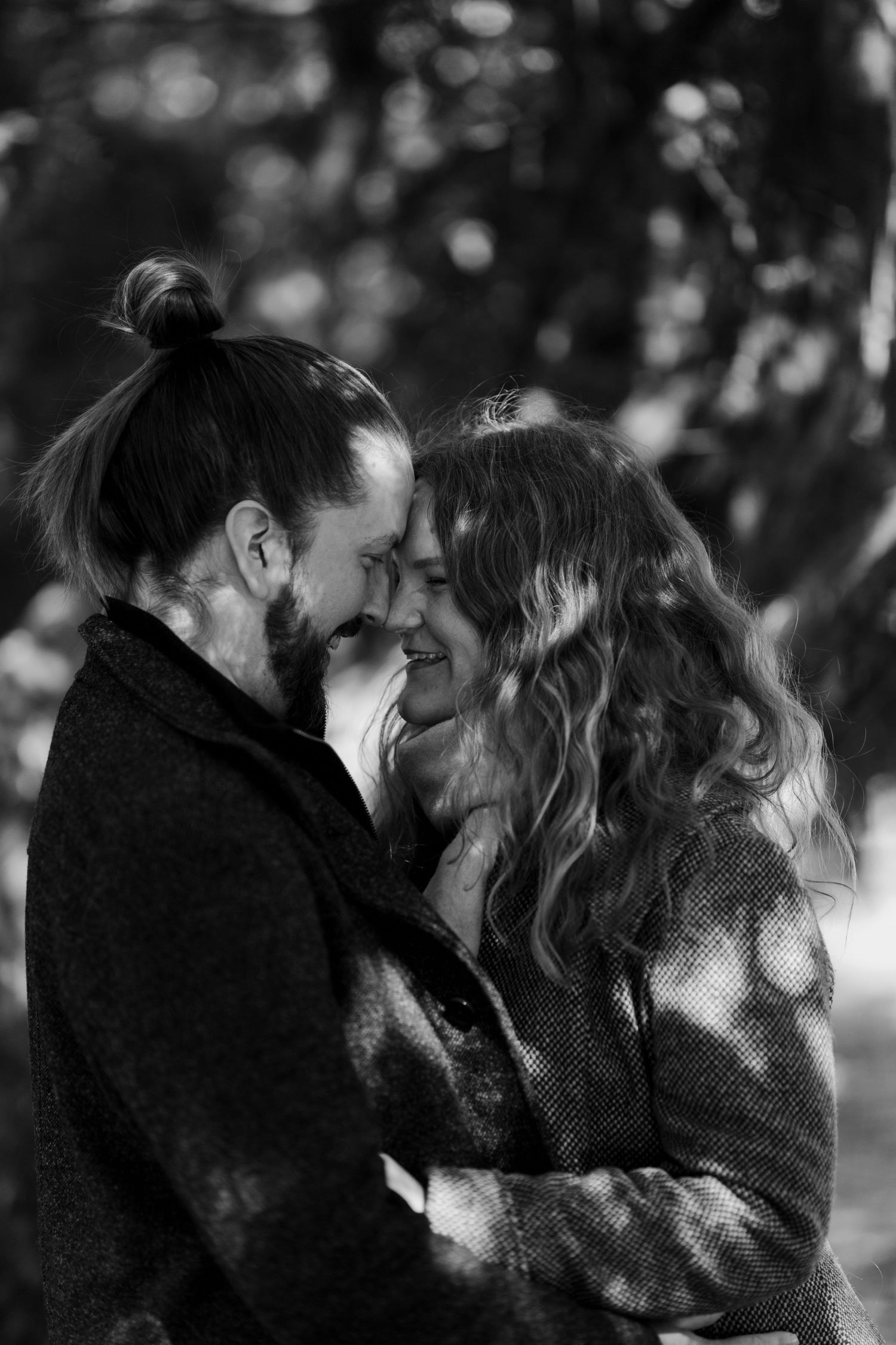 Black and white portrait of couple sharing tender moment in moody lighting.