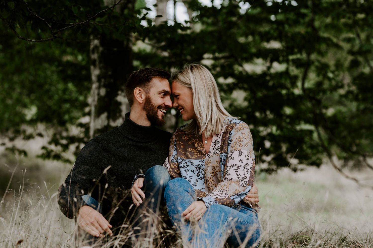 Romantic couple sharing intimate moment while sitting in rustic outdoor setting.