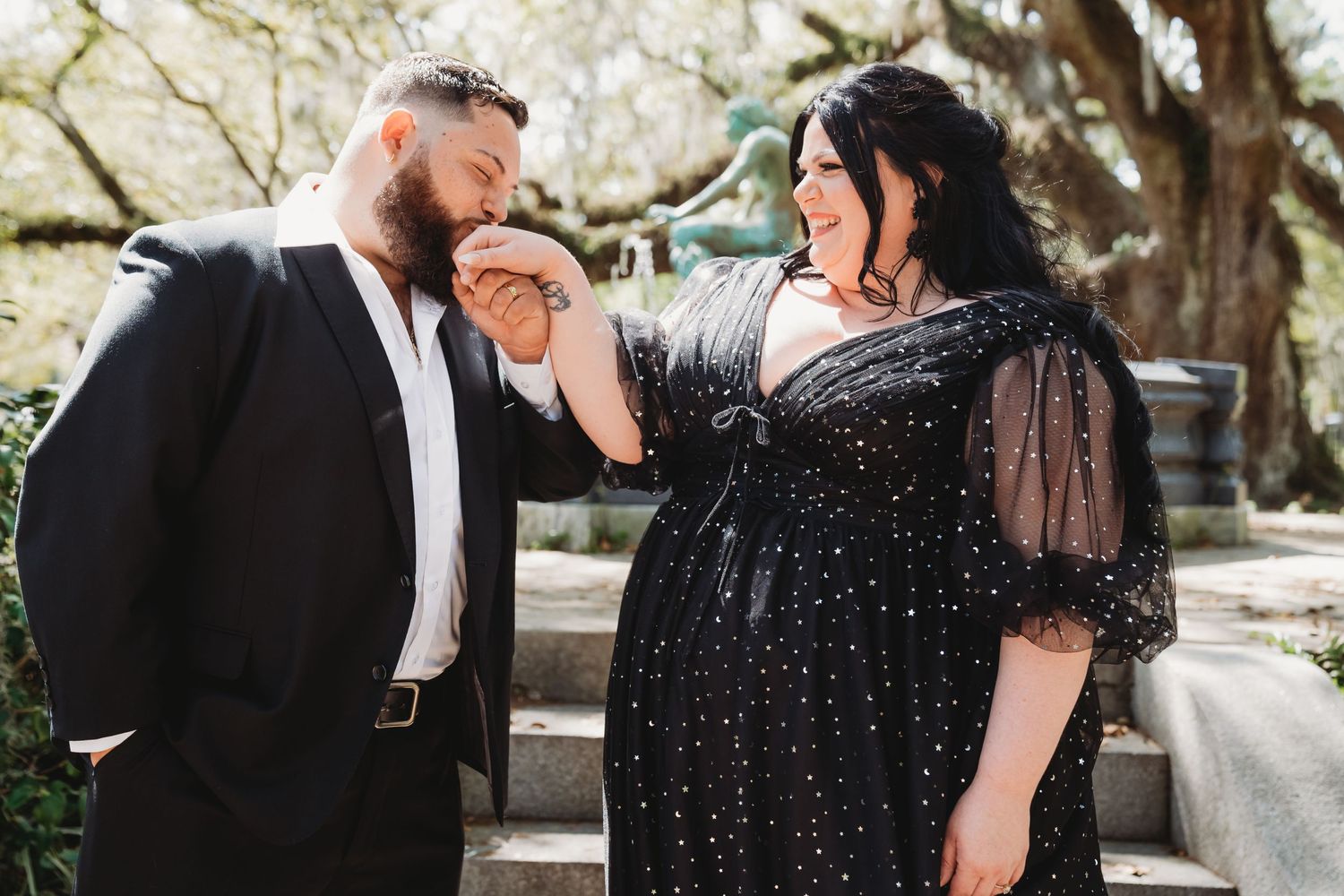 Couple in formal attire sharing romantic moment outdoors at a garden.