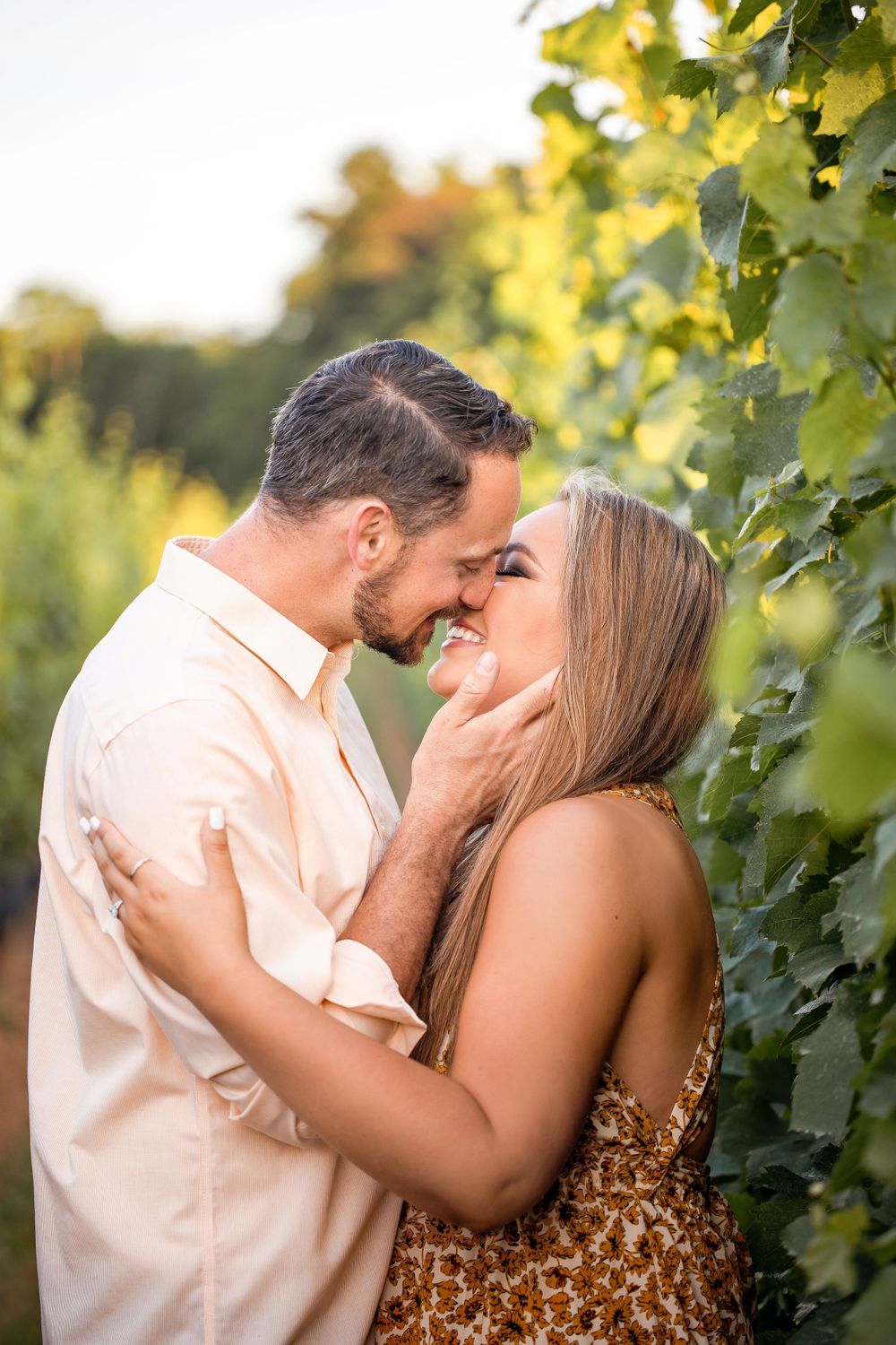 A romantic moment captured between a couple in a sunlit vineyard setting.
