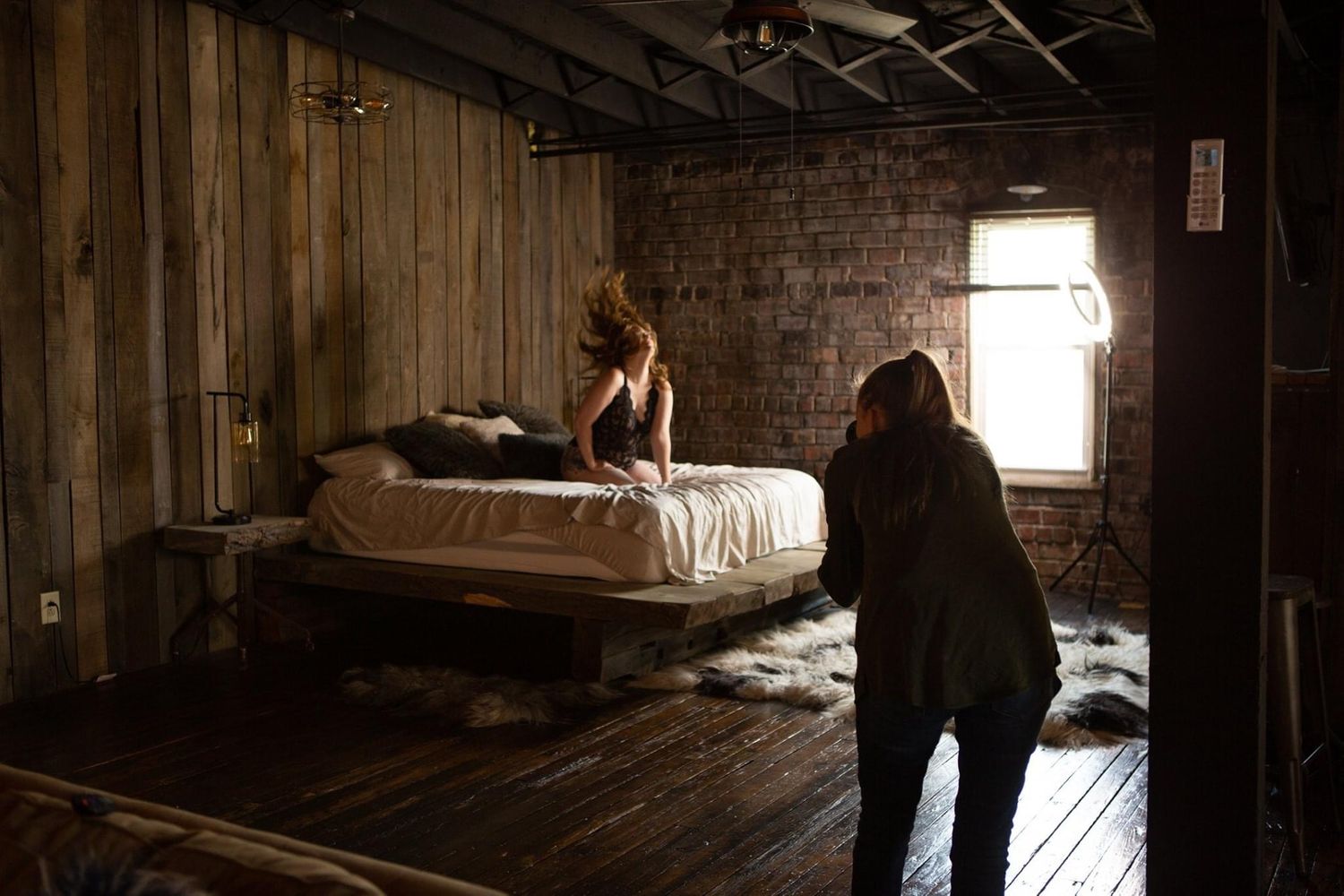 Dark rustic room with wooden walls and dramatic window lighting.
