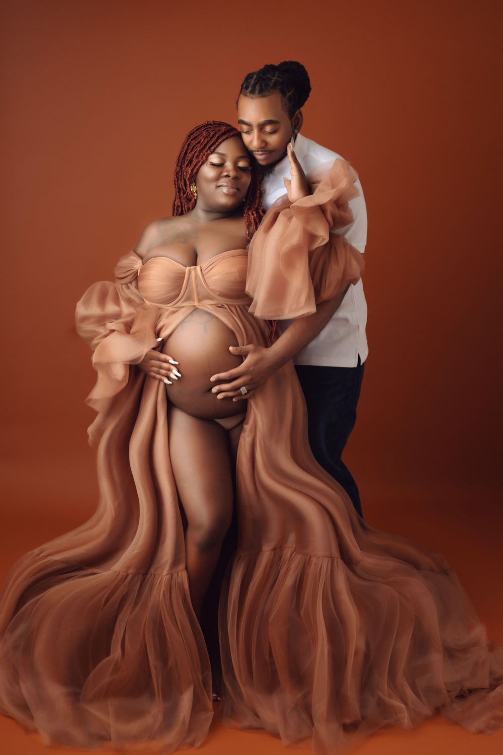 Intimate maternity portrait series featuring couple in warm brown tones and flowing fabric.