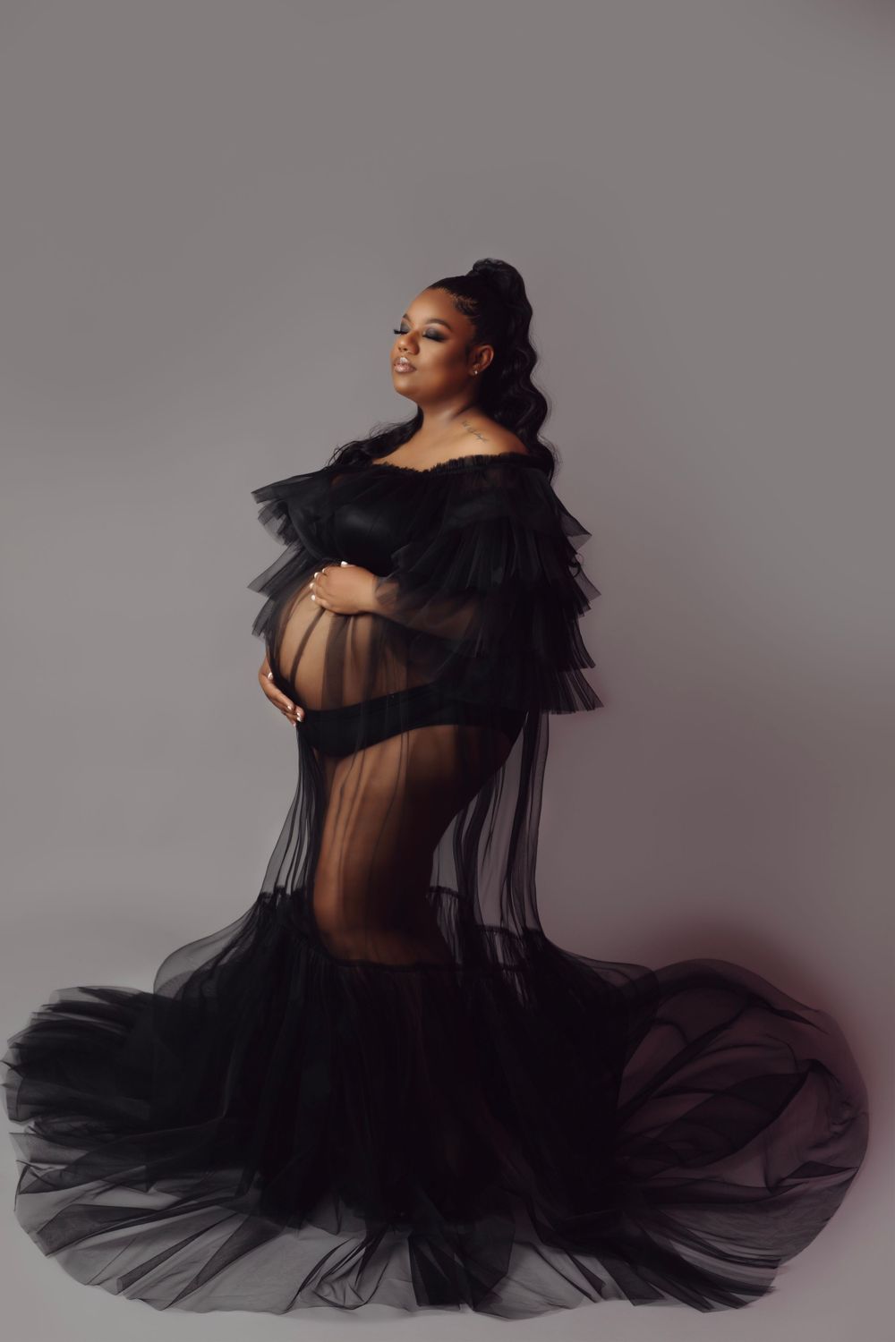 Artistic maternity photos featuring flowing black tulle fabric in dramatic lighting.