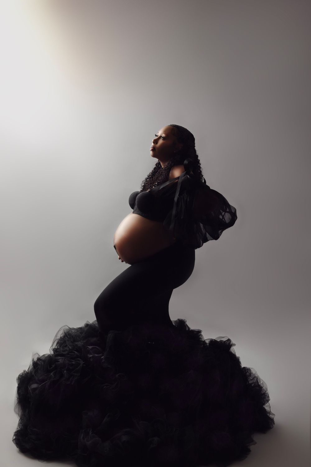 Dramatic silhouette maternity photos against light background showing artistic poses.
