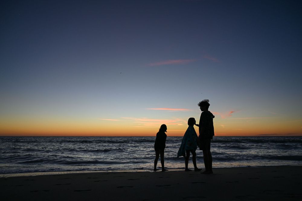 Silhouettes watching a colorful sunset over the ocean.