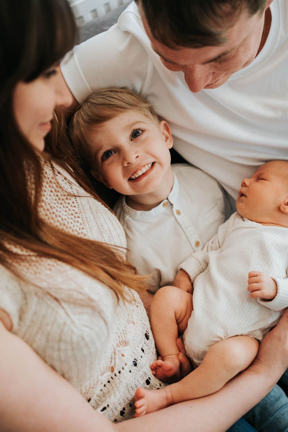 brat trzyma noworodka i uśmiecha się do mamy - fotograf noworodkowy Kraków