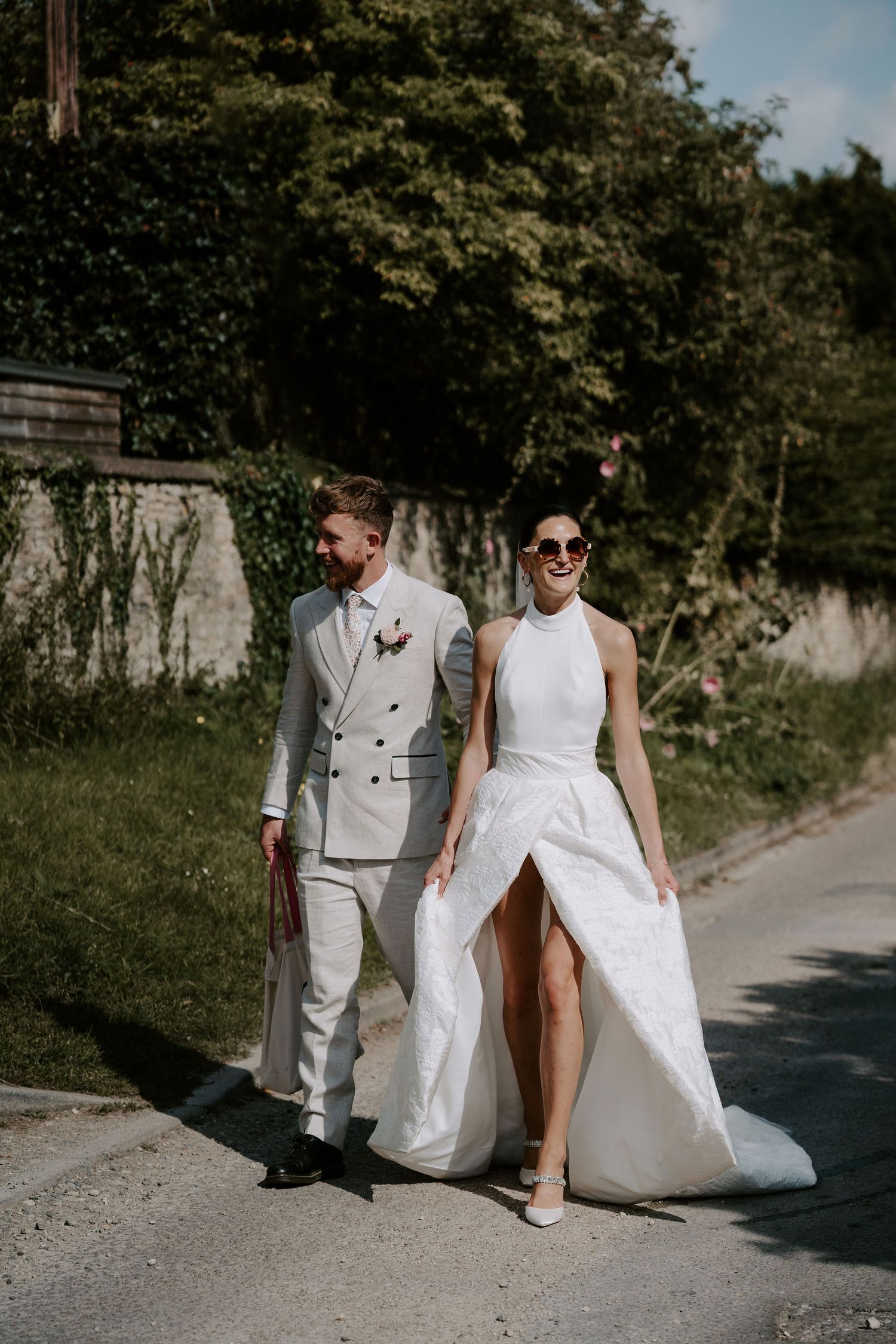 bride and groom wearing sunglasses walking to marquee laughing in islip, oxfordshire