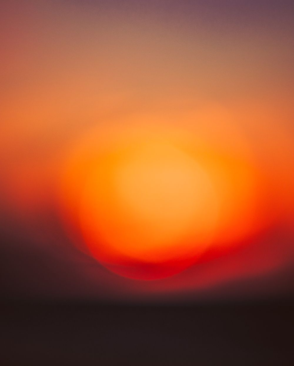A blurred orange and red sunset creating an abstract gradient effect in the sky.
