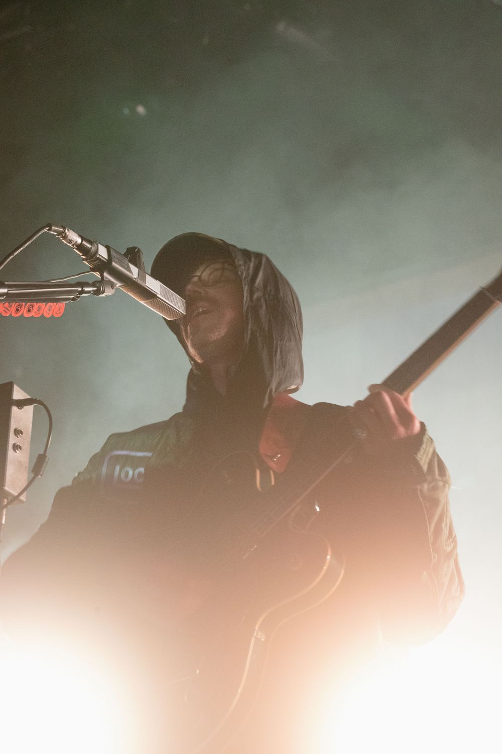 Silhouetted performer singing into microphone during atmospheric concert performance.