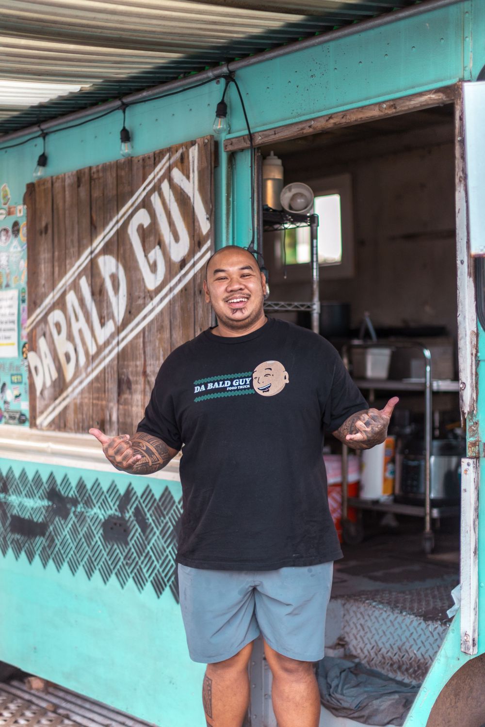 Person smiling in front of turquoise painted Bad Guy shop entrance.