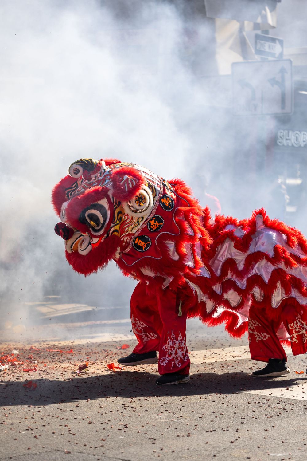 Traditional red Chinese lion dance costume performing in smoky street atmosphere.