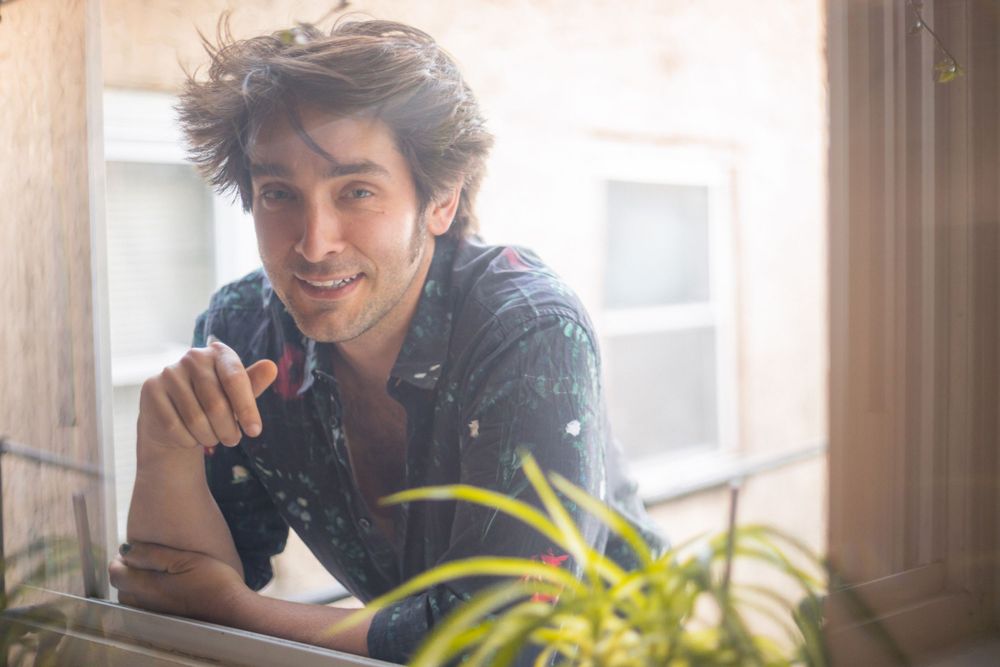 Candid indoor portrait with natural window lighting and houseplant.