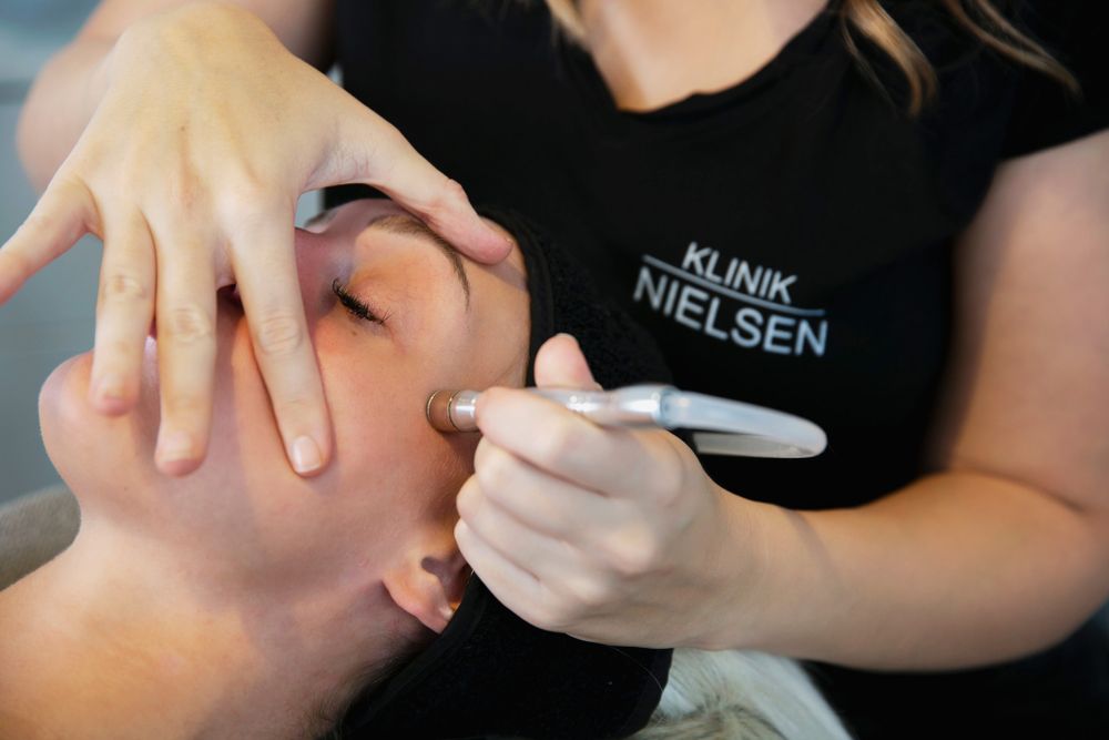 Hudplejeprofessionel påfører en ansigtsmaske under en skønhedsbehandling.