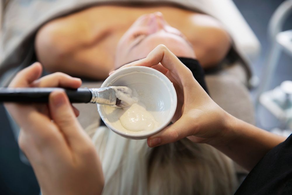 En kosmetolog påfører en ansigtsbehandling med pensel under en spa-behandling.