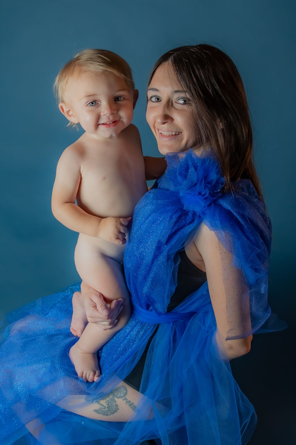 Studio portrait against blue backdrop featuring flowing blue tulle fabric.