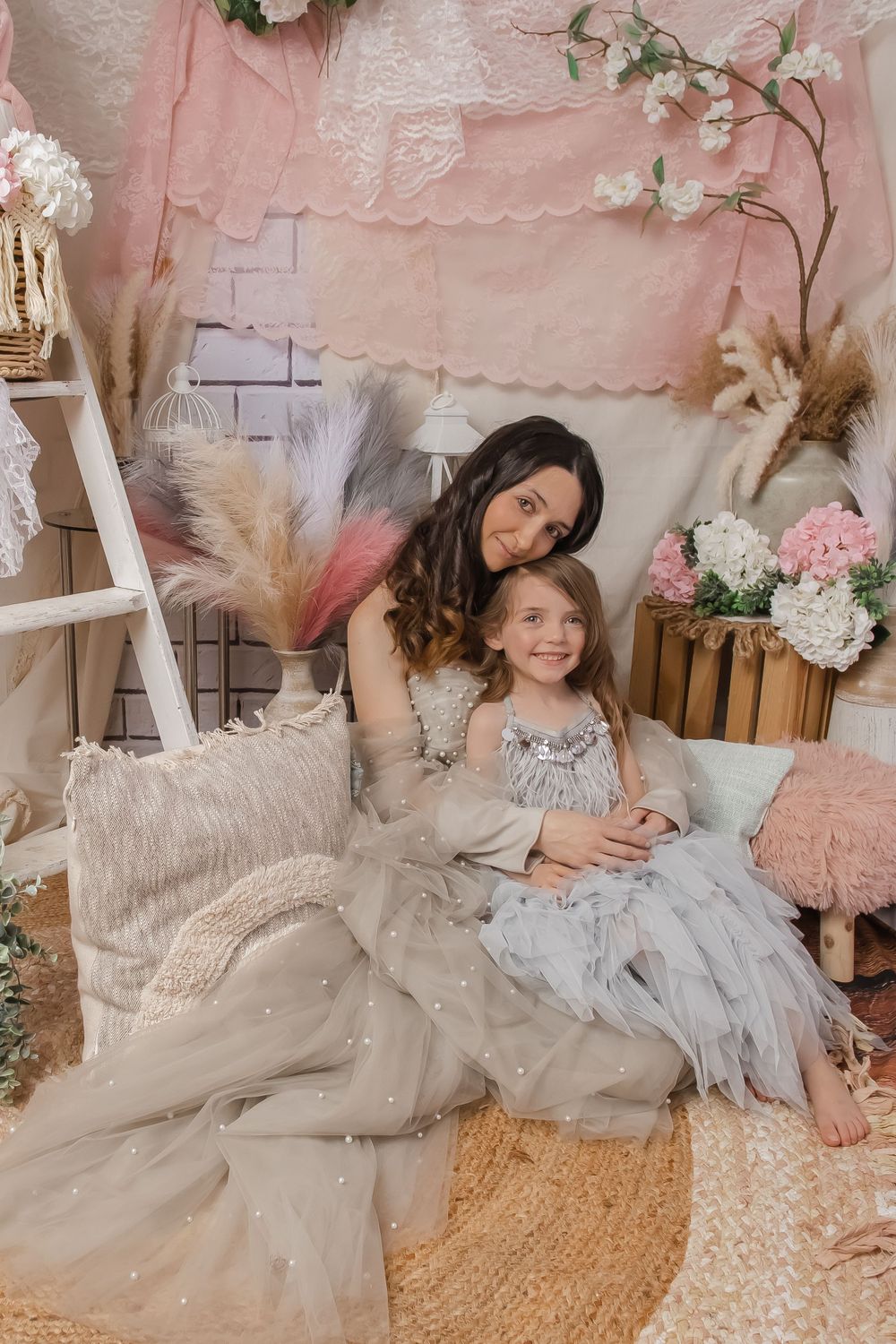 A dreamy portrait session with floral decorations and soft pink tones in a cozy indoor setting.