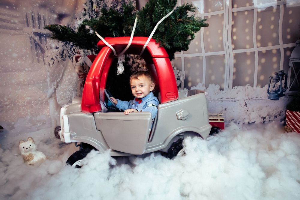 A toy car Christmas photo setup with fake snow and festive decorations.