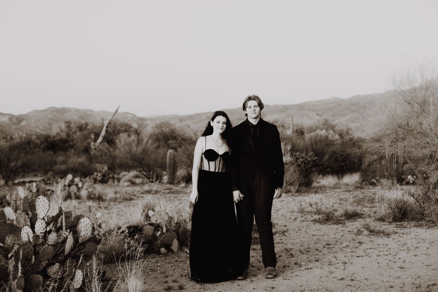 Black and white desert landscape photo with couple in formal attire.