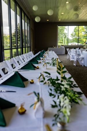 Wedding reception tables decorated with white linens, green accents and floral centerpieces.