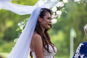 A wedding ceremony moment captured outdoors with flowing white veil in natural lighting.