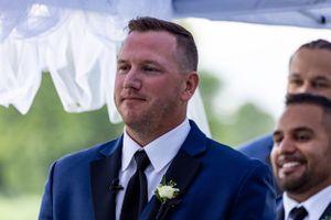 Emotional wedding ceremony moment under white fabric decorations outdoors.