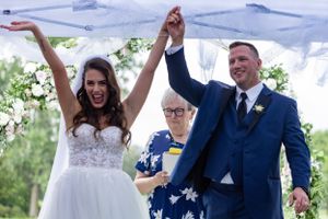 Joyful celebration moment during outdoor wedding ceremony under white tent.