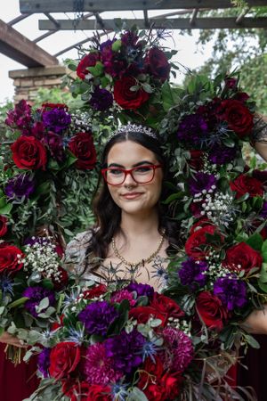 A bridal portrait framed by a stunning wreath of red and purple flowers with greenery.