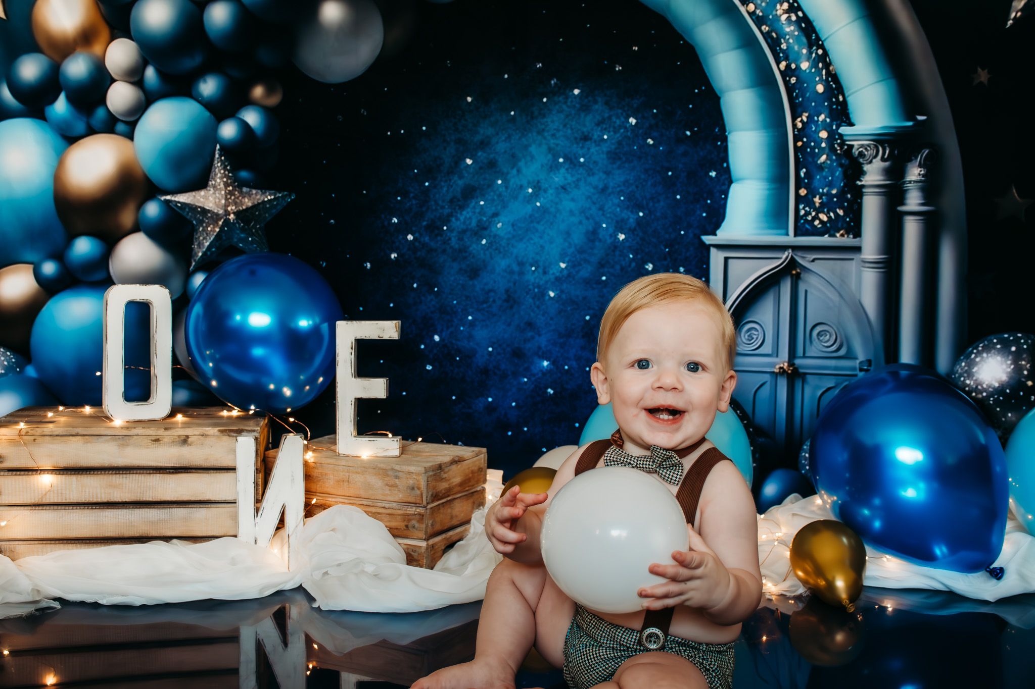 Birthday celebration setup with ONE letters, balloons, and starry backdrop.