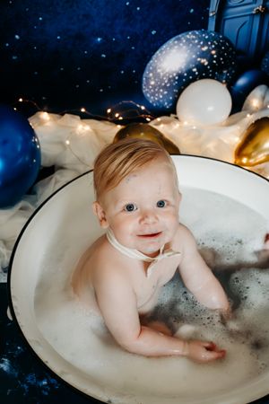 Bath time photo in vintage basin with starry night backdrop and balloons.