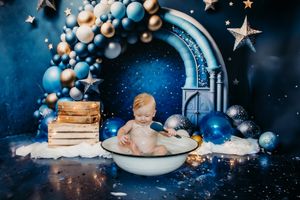 Wide shot of bath time setup with wooden crates and blue balloon arch.
