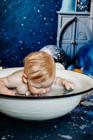 Overhead view of bath time moment in vintage white basin against starry background.