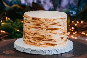 Rustic layered wedding cake with textured frosting and warm lighting.