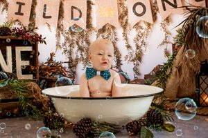 A bath-themed photo setup with vintage tub, pinecones, and 'Wild One' banner.