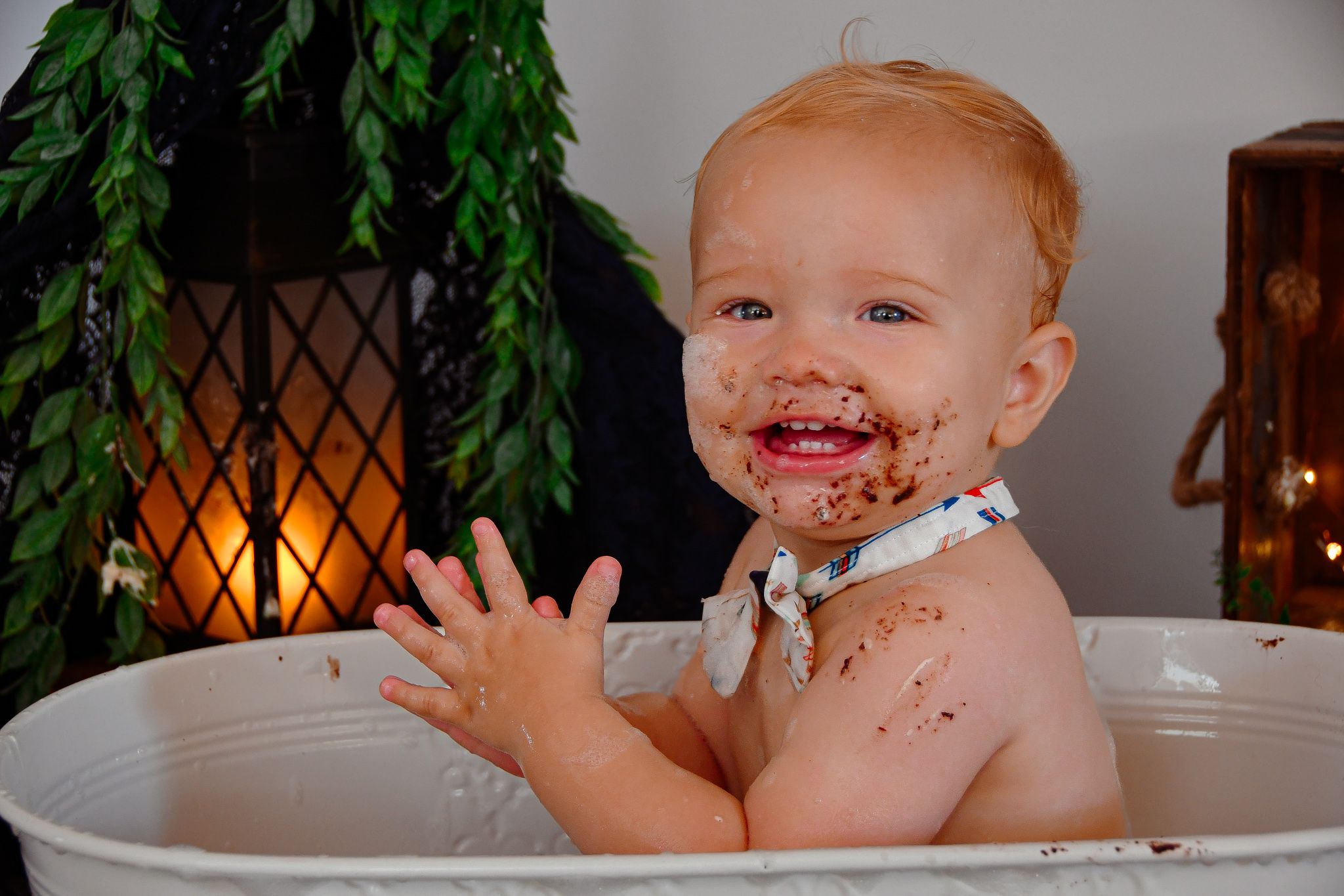 A messy chocolate cake smash photo shoot in a rustic setting with warm lighting.