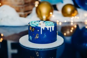 Close-up of navy blue birthday cake with gold stars and white drip decoration.