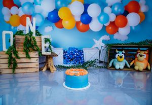 Colorful balloon arch with blue, red, and yellow balloons against a blue background for a party celebration.