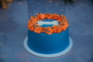Close-up of a blue birthday cake with orange decorative elements on top.