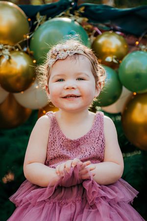 Festive party scene with gold and green balloon decorations in the background.