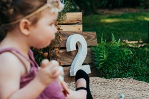White number 2 decoration placed outdoors on a natural wooden surface.