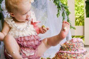Delightful cake smash photo series with vintage-style dress and floral decorations.
