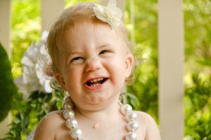 Joyful outdoor portrait series against white picket fence with natural greenery.