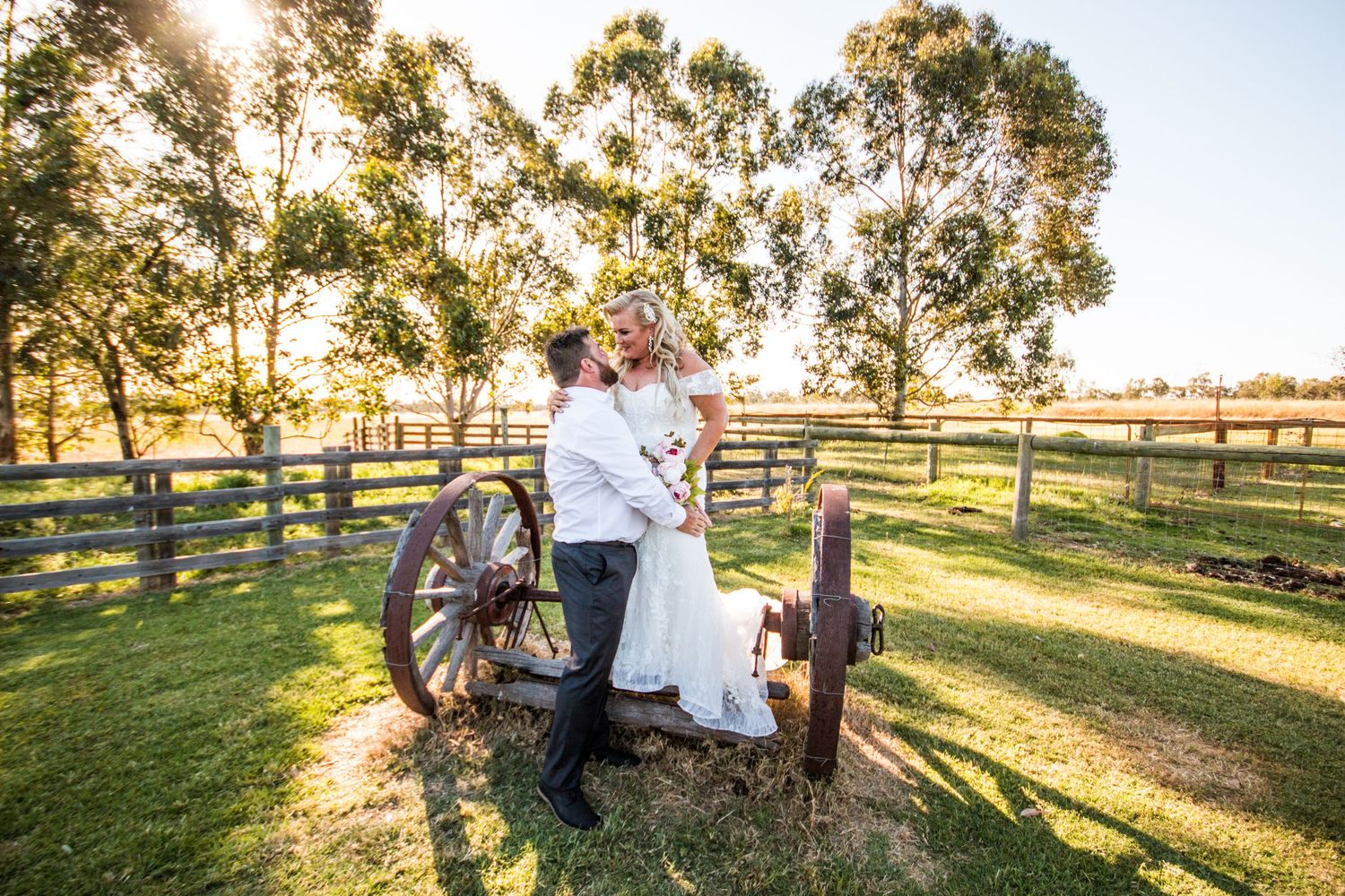 Romantic countryside portrait with antique wagon wheel at golden sunset.