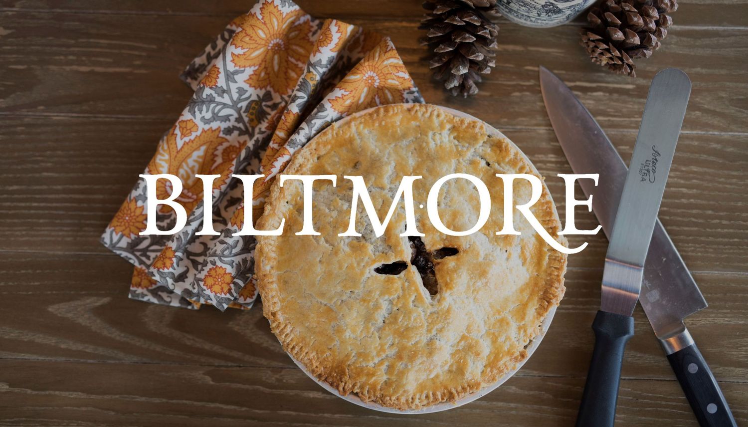Biltmore branded pie with pinecones and rustic styling on wooden surface.